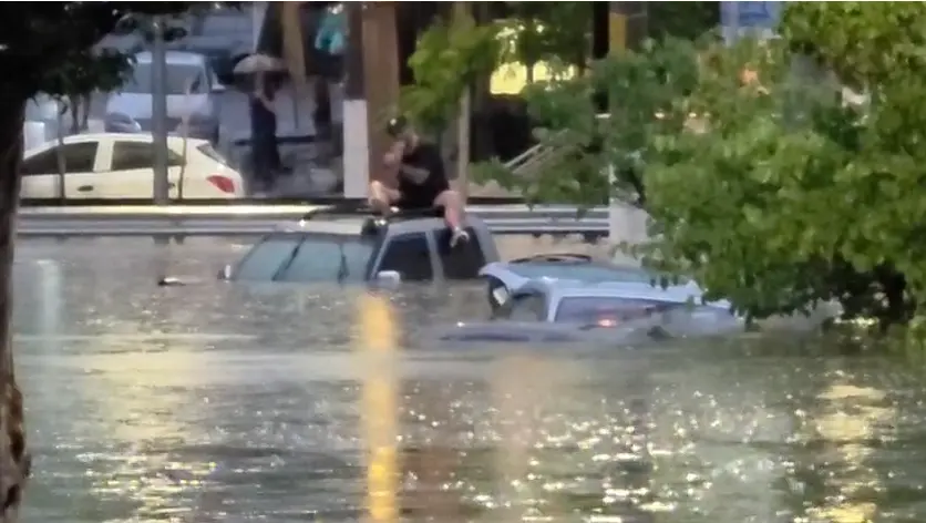 Homem sobe em carro para escapar de alagamento em SP