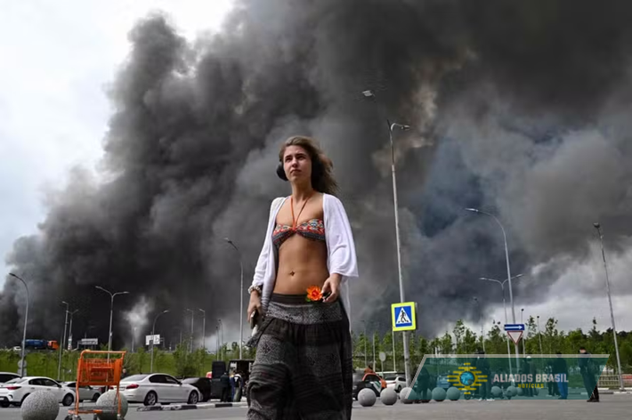 Jovem 'alheia' a explosões em Moscou se destaca diante de imensa coluna de fumaça provocada por ataque ucraniano