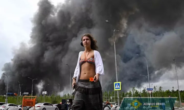 Jovem 'alheia' a explosões em Moscou se destaca diante de imensa coluna de fumaça provocada por ataque ucraniano